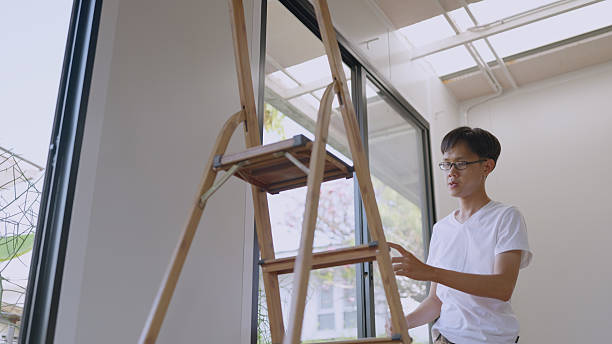 Asian young man is measuring a window to install curtains. DIY.