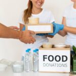 smiley-volunteers-with-gloves-handing-boxes-with-food-donation_23-2148733763