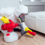 pest control worker lying on floor and spraying pesticides in bedroom.