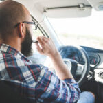 man smoking a vape in a car