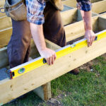 Carpenter checking level of deck boards
