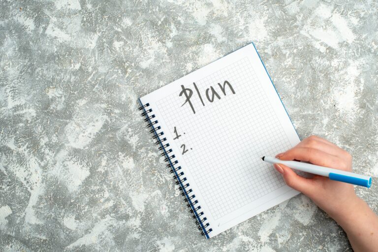 overhead-view-hand-writing-spiral-notebook-gray-background (1)