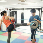 Mature adult woman training with male instructor at boxing gym