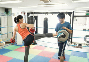 Mature adult woman training with male instructor at boxing gym
