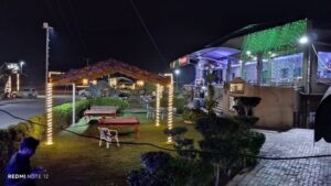 Outdoor restaurant seating area at night with decorative lights, gazebo, and greenery.