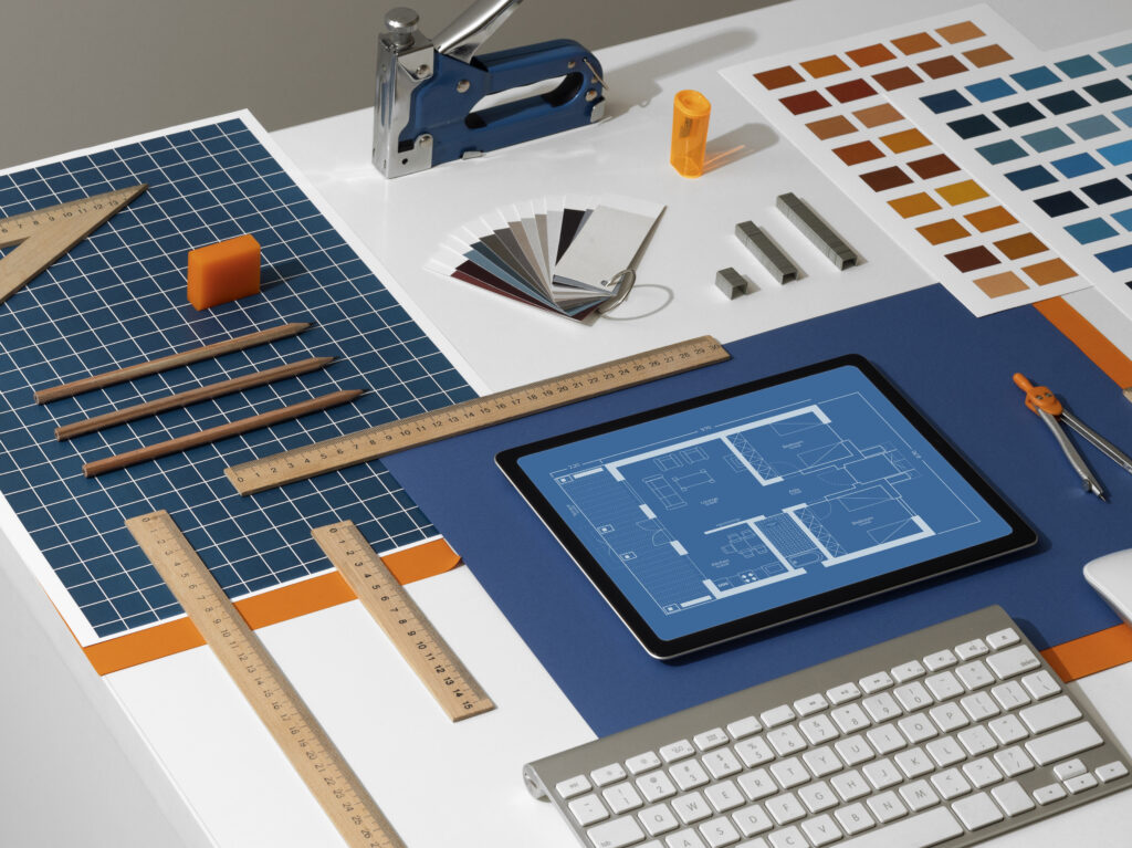 "Architect’s desk with digital CAD blueprint on tablet, rulers, pencils, and color samples."