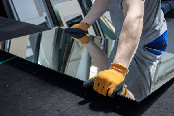 the glazier picks up the mirror from the table in the glass factory