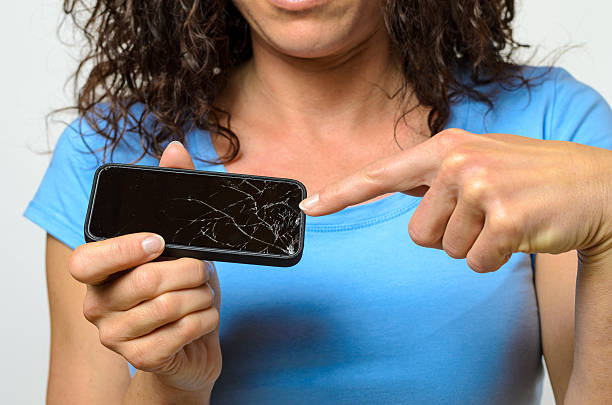 Close up of one woman in blue shirt holding broken mobile phone in her hands
