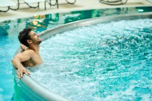 young-relaxed-man-enjoying-hot-tub-while-spending-day-wellness-center (1)
