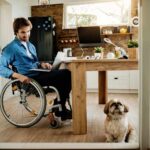 happy-businessman-wheelchair-looking-his-dog-while-working-laptop-home (1)