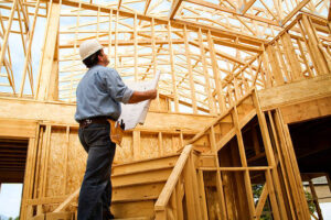 A structural engineer inspecting the exposed wooden studs and roof trusses of a property built using timber frame house kits prices UK, holding blueprints on-site.