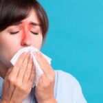 A-woman-with-inflamed-sinus-areas-blowing-her-nose-indicating-chronic-sinusitis-551x431