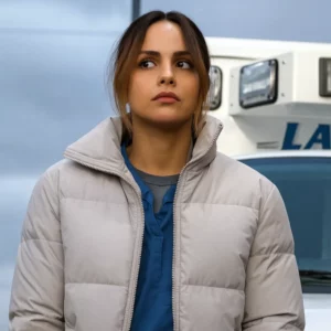 Woman wearing a light grey quilted puffer jacket with a high collar, standing outdoors in a casual streetwear look.