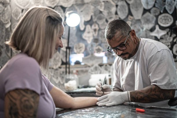 Tattoo artist preparing to tattoo a woman at a tattoo studio