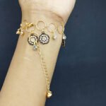 Gold chain bracelet with flower charms and small crystals on wrist.