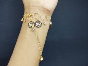 Gold chain bracelet with flower charms and small crystals on wrist.