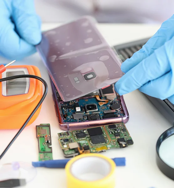Technician wearing blue gloves repairing a smartphone by inspecting its internal components and circuit board using electronic repair tools.