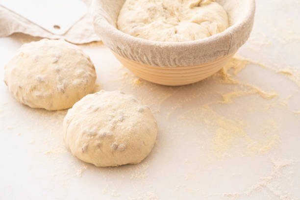 Baking bread. Dough in proofing basket on wooden table with flour. Top view.